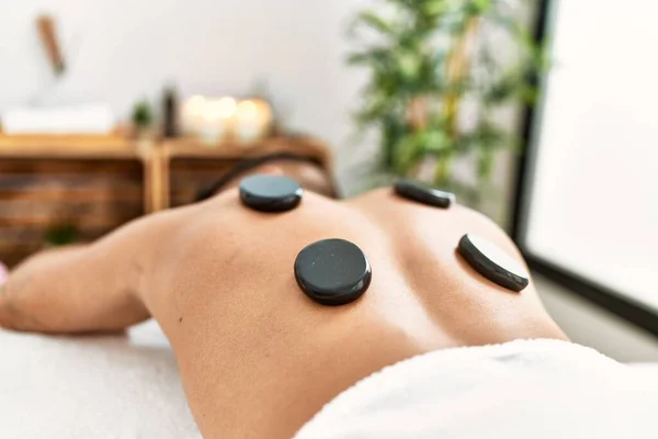 Young Hispanic Man Relaxed Having Back Massage Using Black Stones — стоковое фото