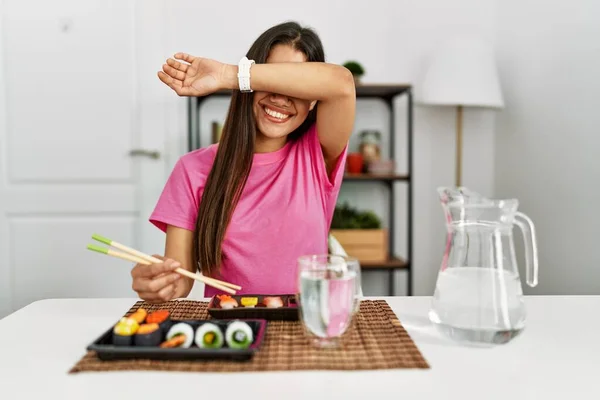 年轻的黑发女人用筷子吃寿司 开心地笑着玩着 用手摸着脸看竹子 很惊讶也很兴奋 — 图库照片