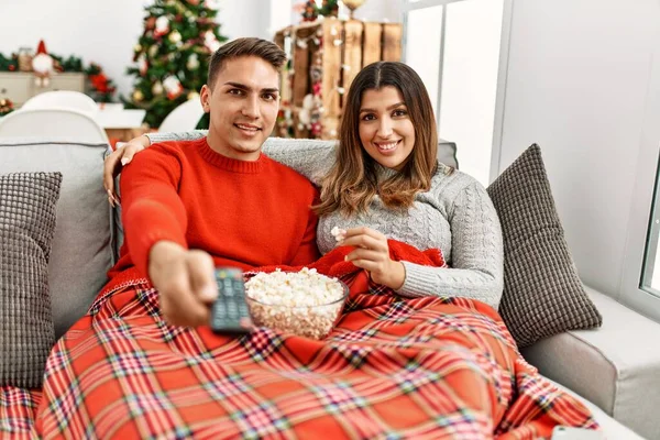 Young couple watching movie and eating popcorn at home.