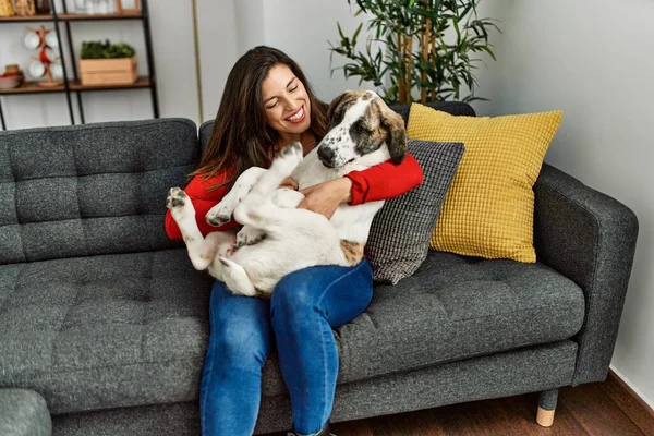 Young woman hugging dog sitting on sofa at home