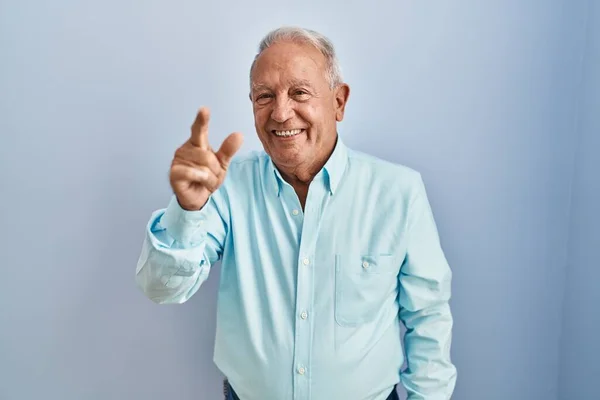 一个白发苍苍的老人站在蓝色的背景上 用手指指了指二号 面带微笑 自信而快乐 — 图库照片