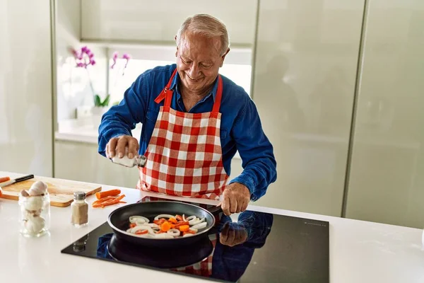 Ηλικιωμένος Άνθρωπος Χαμογελά Αυτοπεποίθηση Ρίχνει Αλάτι Στο Τηγάνι Στην Κουζίνα — Φωτογραφία Αρχείου
