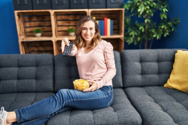 Evdeki kanepede oturan genç bir kadın.