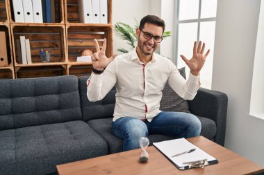 Danışma ofisinde çalışan sakallı genç İspanyol adam sekiz numaralı parmaklarını gösterip işaret ederken kendinden emin ve mutlu gülümsüyor.. 