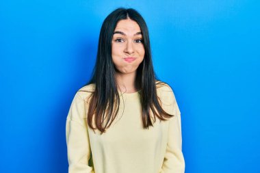 Sıradan bir kazak giyen esmer bir kadın komik suratlı, yanak şişiriyor. Havayla şişmiş ağız, çılgın bir ifade.. 