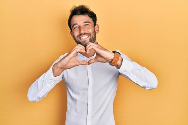 Sakallı, sıradan, beyaz tişörtlü, aşık bir adam. Elleriyle kalp sembolü çiziyor. romantik kavram. 