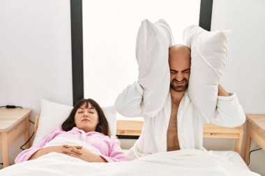 Yatakta horlayan bir kadın varken, kulaklarında yastıkla İspanyol bir adam sinirlendi..