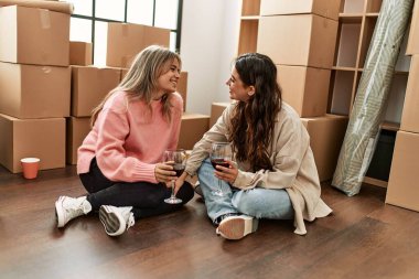 Gülümseyen genç çift yeni evinde kırmızı şarapla kadeh kaldırıyor.