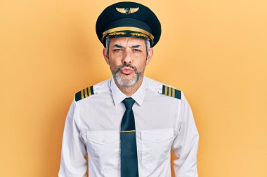 Gri saçlı, uçak pilotu üniforması giyen yakışıklı orta yaşlı bir adam. Havada öpüşürken kameraya bakıyor. Güzel ve seksi. aşk ifadesi. 