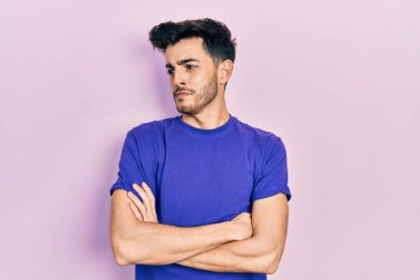 Sıradan tişört giyen genç İspanyol adam kollarını kavuşturmuş, ikna olmuş ve kendinden emin bir şekilde yana bakıyor. 