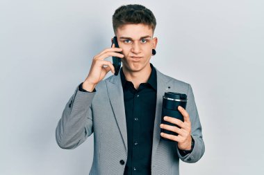 Akıllı telefon kullanan, kuşkucu ve gergin bir fincan kahve içen, kulakları genişlemiş, genç beyaz bir çocuk sorun yüzünden üzgün. negatif kişi. 