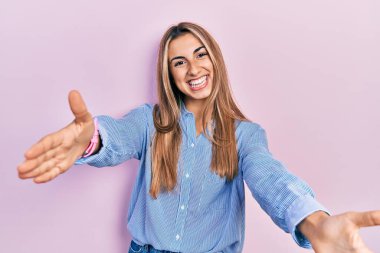 Güzel İspanyol kadın, gündelik tişört giyip kameraya bakıyor. Sarılmak için kollarını açmış gülümsüyor. Mutluluğu kucaklayan neşeli bir ifade.. 