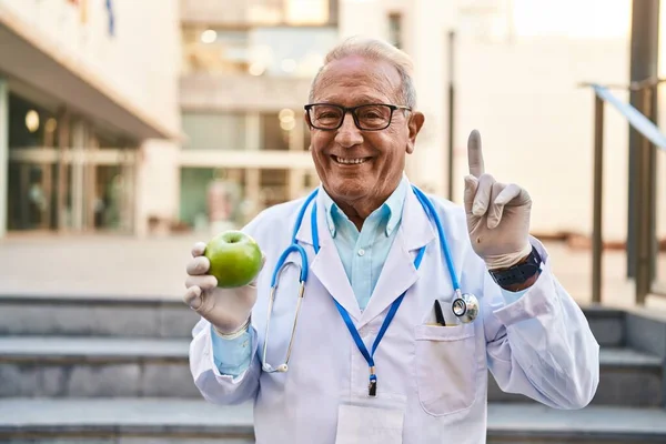 Starszy Lekarz Siwymi Włosami Trzymający Zdrowe Zielone Jabłko Zaskoczony Pomysłem — Zdjęcie stockowe