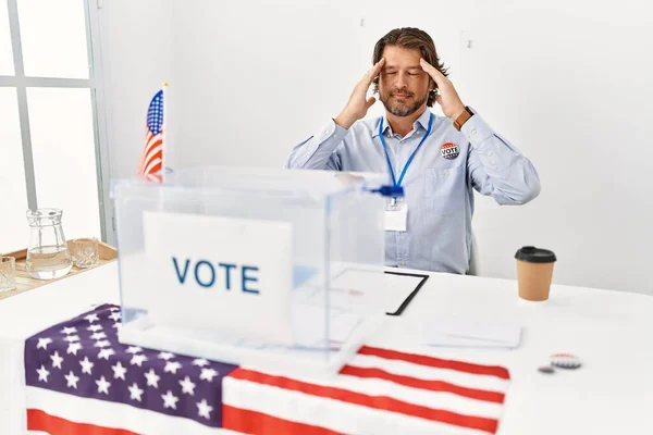 一个英俊的中年男人坐在投票站里 手牵着手 因为压力而头疼 偏头痛 — 图库照片
