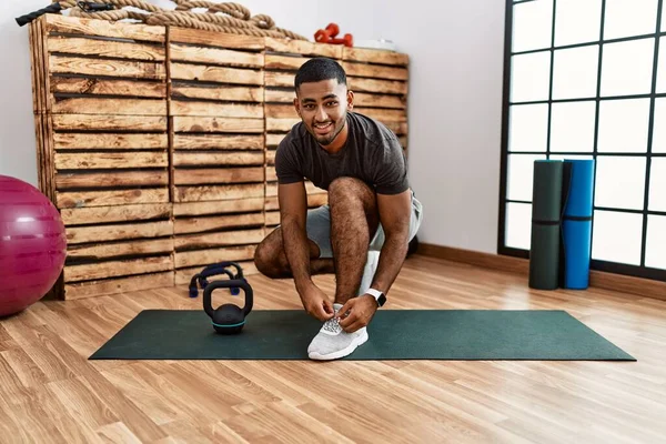 Young arab man smiling confident doing shoelace at sport center