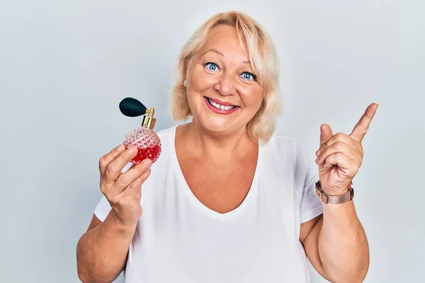 Middle Age Blonde Woman Holding Perfume Smiling Happy Pointing Hand — Fotografia de Stock