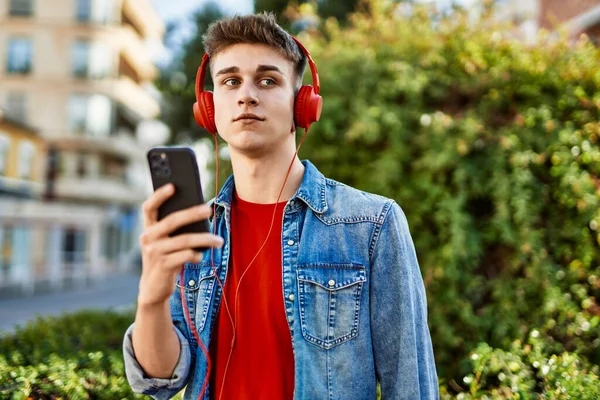 市内で音楽を聴くヘッドフォンを身に着けている若い白人男性 — ストック写真
