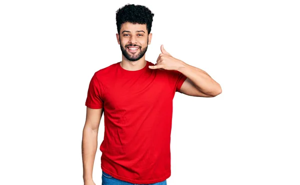 ひげを生やした若いアラブ人は 電話で話すような手や指で携帯電話のジェスチャーをして笑顔でカジュアルな赤いTシャツを着ていた コミュニケーションの概念 — ストック写真