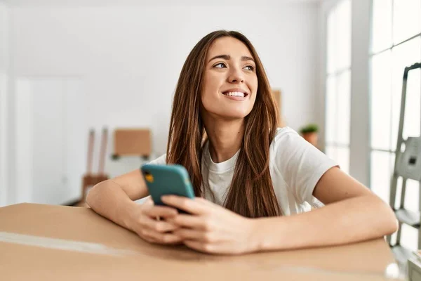 Young Hispanic Woman Smiling Confident Using Smartphone New Home — стоковое фото