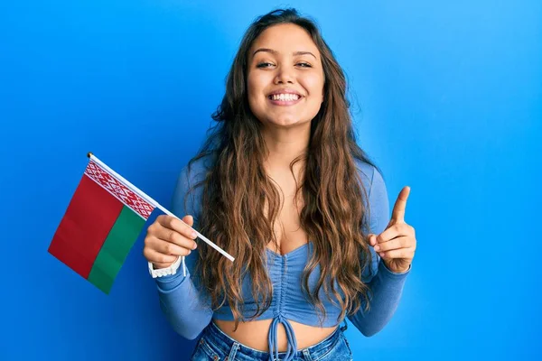 Młoda Latynoska Trzymająca Flagę Belarusa Uśmiechnięta Pomysłem Lub Pytaniem Wskazującym — Zdjęcie stockowe