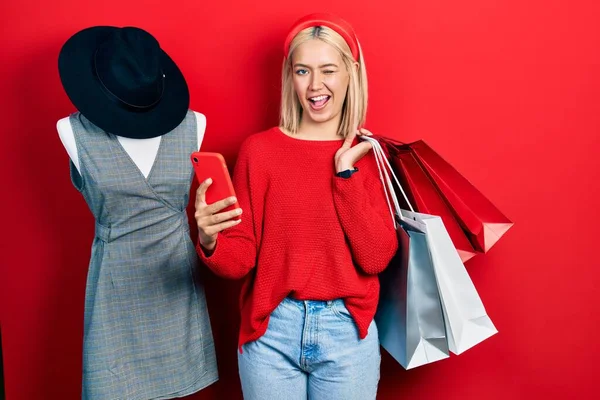 Beautiful Blonde Woman Holding Shopping Bags Smartphone Winking Looking Camera — 图库照片