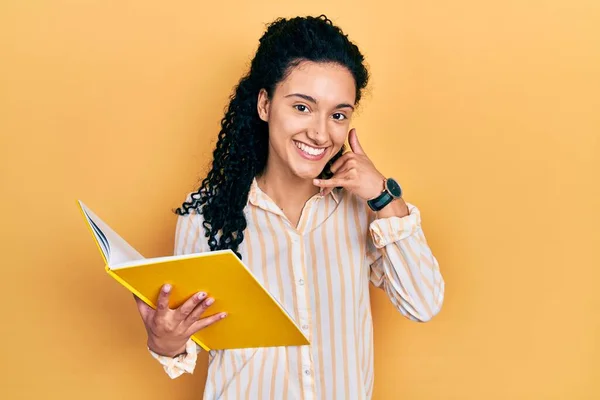 Young Hispanic Woman Curly Hair Holding Book Smiling Doing Phone — Stockfoto