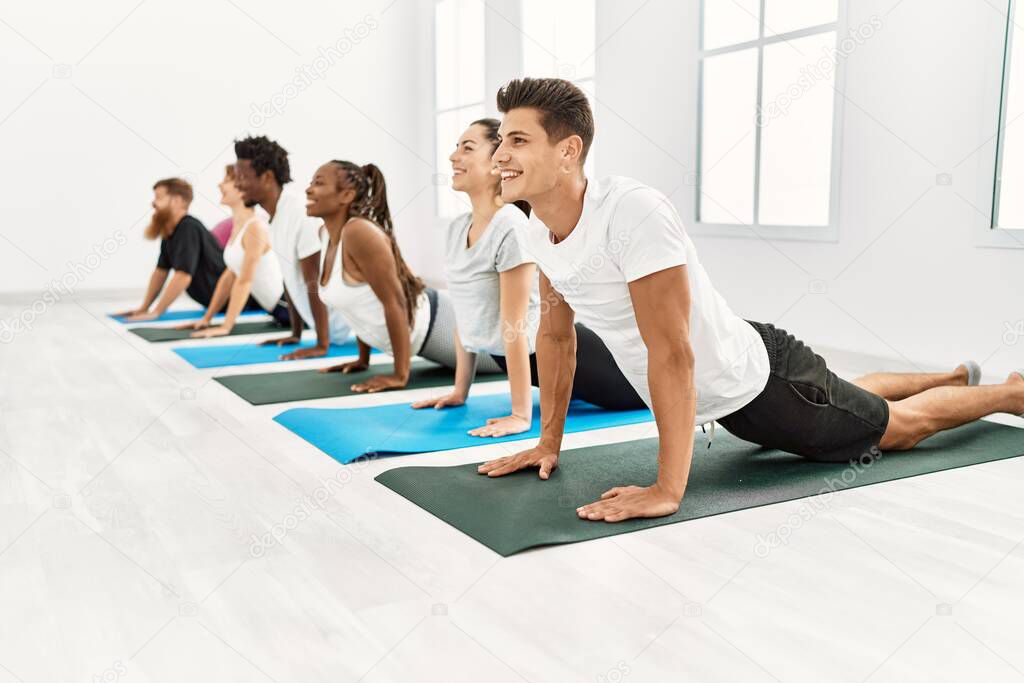 Group of young people smiling happy training yoga at sport center.