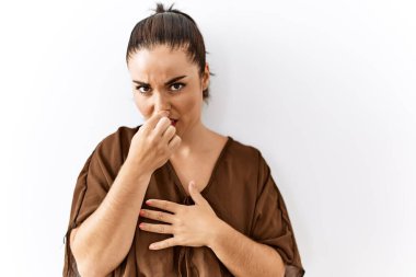 Genç esmer kadın izole edilmiş arka planda duruyor. Kokuşmuş ve iğrenç bir koku alıyor. Dayanılmaz bir koku. Kötü kokuyor. 