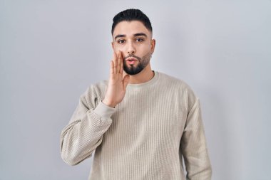 Genç ve yakışıklı bir adam arka planda duruyor. Ağızdan ağıza, gizli dedikodular söylüyor, kötü niyetli konuşmalar fısıldıyor. 