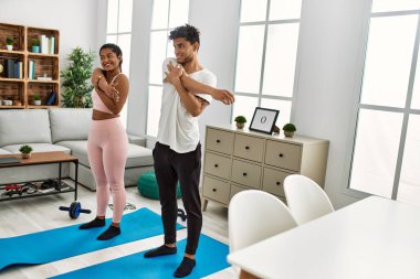 Genç Latin sporcu çift gülümseyerek evde mutlu bir antrenman yapıyor..