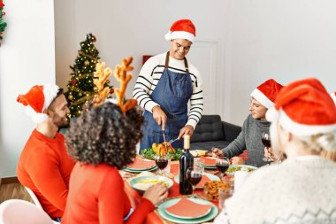 Mutlu bir şekilde gülümseyen bir grup genç adam evde servis etmek için kızarmış hindi kesiyor..