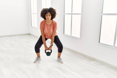 Genç Afrikalı Amerikalı kadın spor merkezinde kettlebell kullanıyor.