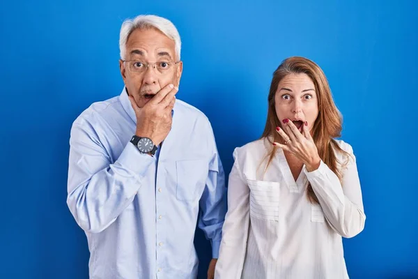 Casal Hispânico Meia Idade Sobre Fundo Azul Olhando Fascinado Com — Fotografia de Stock