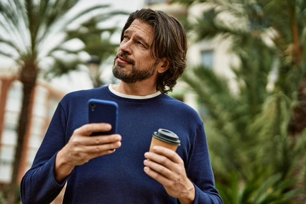 中年男子在公园外面用智能手机喝咖啡 — 图库照片