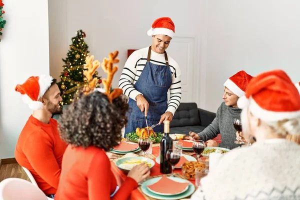 Mutlu bir şekilde gülümseyen bir grup genç adam evde servis etmek için kızarmış hindi kesiyor..