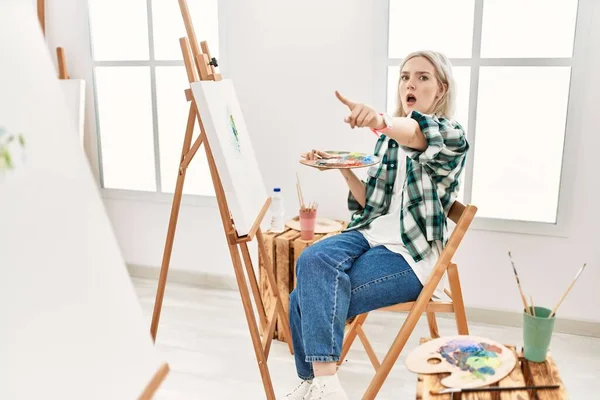 Young Artist Woman Painting Canvas Art Studio Pointing Finger Surprised — Stok fotoğraf