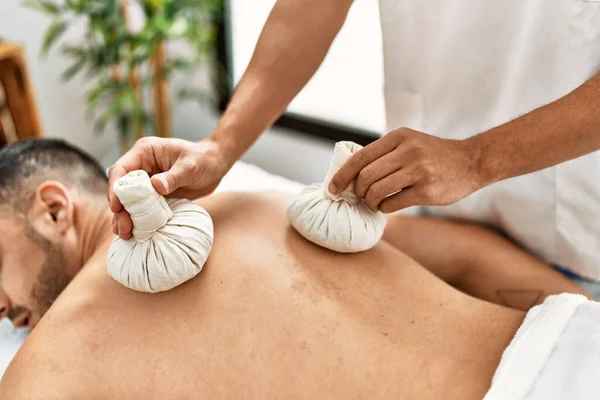 Dos Hombres Hispanos Fisioterapeuta Paciente Masajeando Usando Bolsas Tailandesas Centro —  Fotos de Stock