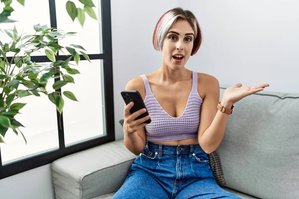 Young Beautiful Woman Using Smartphone Typing Message Sitting Sofa Pointing — Foto Stock