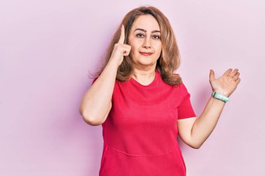 Orta yaşlı, günlük kıyafetler giyen, kafası karışmış ve avuç içi açık bir şekilde fotokopi alanını gösteren ve alnını işaret eden beyaz bir kadın. Bunu bir düşün.. 