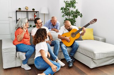 Bir grup orta yaşlı arkadaş evdeki kanepede oturup klasik gitar çalıyorlar..