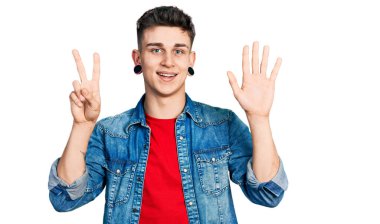 Kulakları genişlemiş, sıradan kot ceket giyen genç beyaz çocuk yedinci parmaklarını gösterirken kendinden emin ve mutlu bir şekilde gülümsüyor.. 