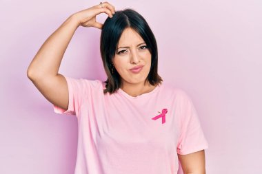 Tişörtüne pembe kanser kurdelesi takan genç İspanyol kadın kafasını karıştırıyor ve soruyu merak ediyor. Şüpheyle kararsız, kafa kafaya düşünerek. Düşünceli kavram. 