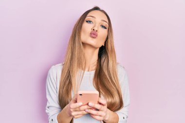 Güzel ve seksi bir şekilde öpüşürken kameraya bakarak akıllı telefon mesajı yazan genç sarışın kız. aşk ifadesi. 