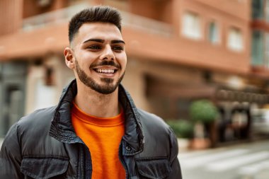 Yakışıklı, sakallı, neşeli ve kendine güvenen, kışlık palto giyen bir İspanyol.