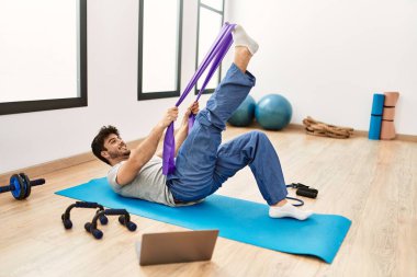 Spor salonunda online spor dersi aldığı için mutlu gülümseyen İspanyol genç adam..