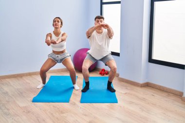 Genç adam ve kadın spor merkezinde egzersiz yapıyor.