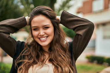 Genç İspanyol kadın gülümseyerek şehirde mutlu mesut dikiliyor..