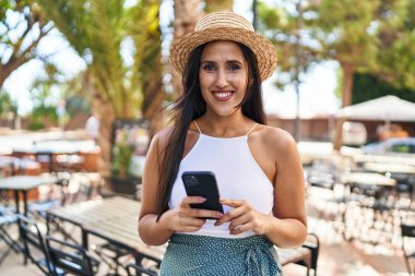Sokakta akıllı telefon kullanan, kendine güvenen genç İspanyol kadın.