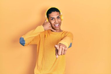 Genç Afro-Amerikalı adam kulaklık takarak müzik dinliyor gülümsüyor telefonda konuşuyor ve seni işaret ediyor. Ara beni.. 