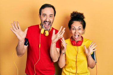 Orta yaşlı bir çift İspanyol kadın ve erkek spor giysisi ve kol bandı takıp çılgınlığı kutluyor ve başarıya hayran kalıyorlar. Kolları havada ve gözleri açık, heyecanlı bir şekilde bağırıyorlar. Kazanan konsept 